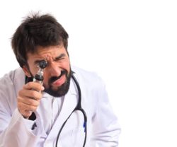 Otorhinolaryngologist with his otoscope over white background